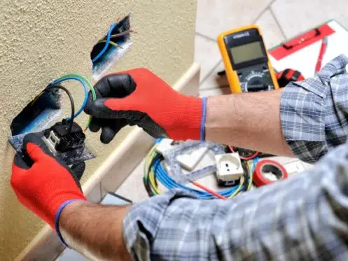 someone with red gloves installing an electrical outlet